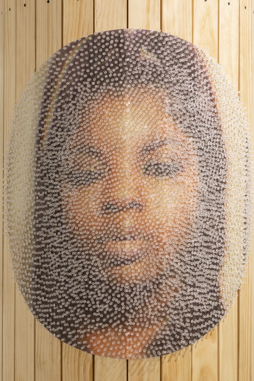 Close up image of woman's face on column, covered in clear tacks