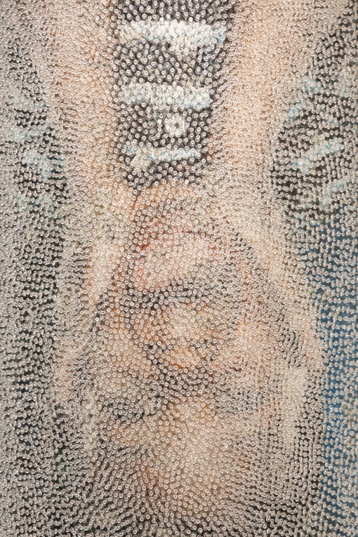 Close up image of person holding face between their two hands, covered in clear tacks
