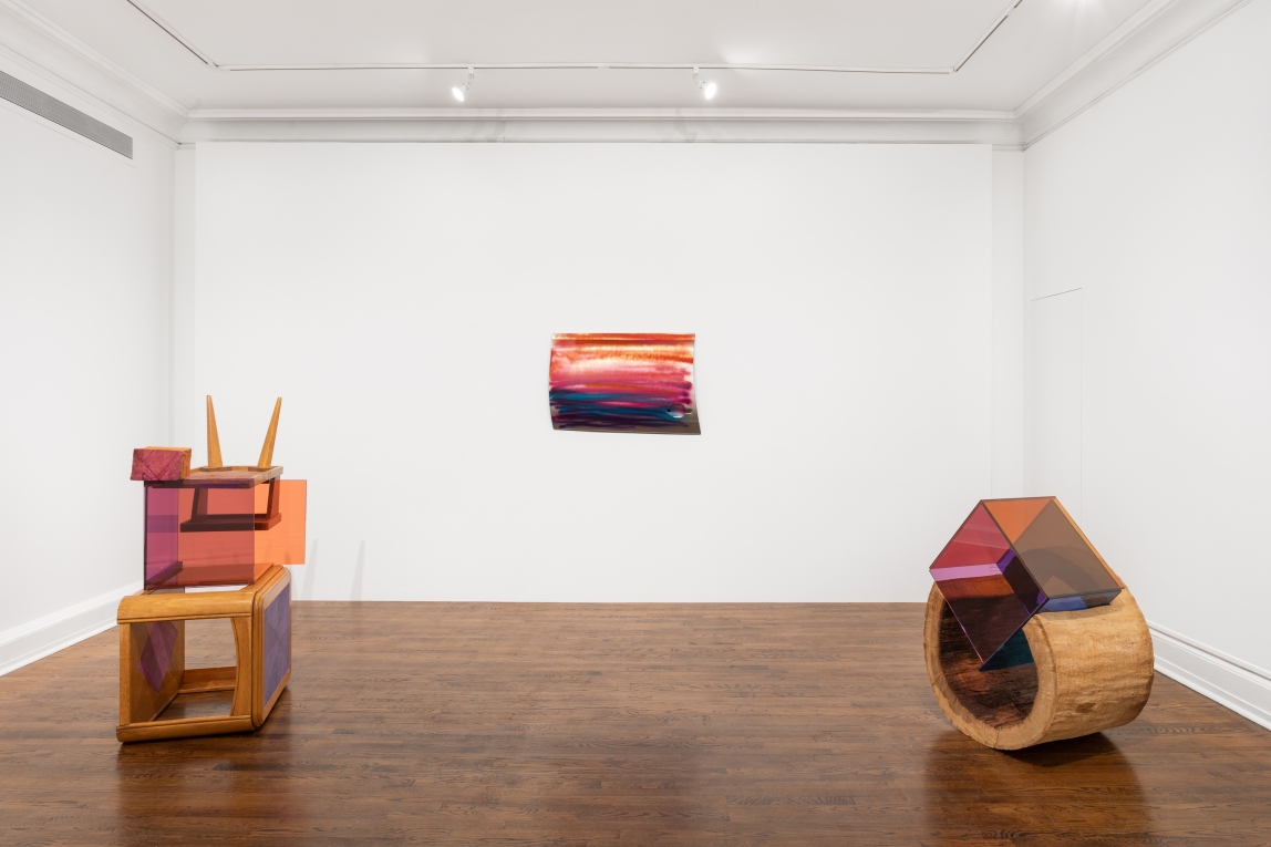 Installation view of artwork hanging on wall and two wood and glass sculptures no floor