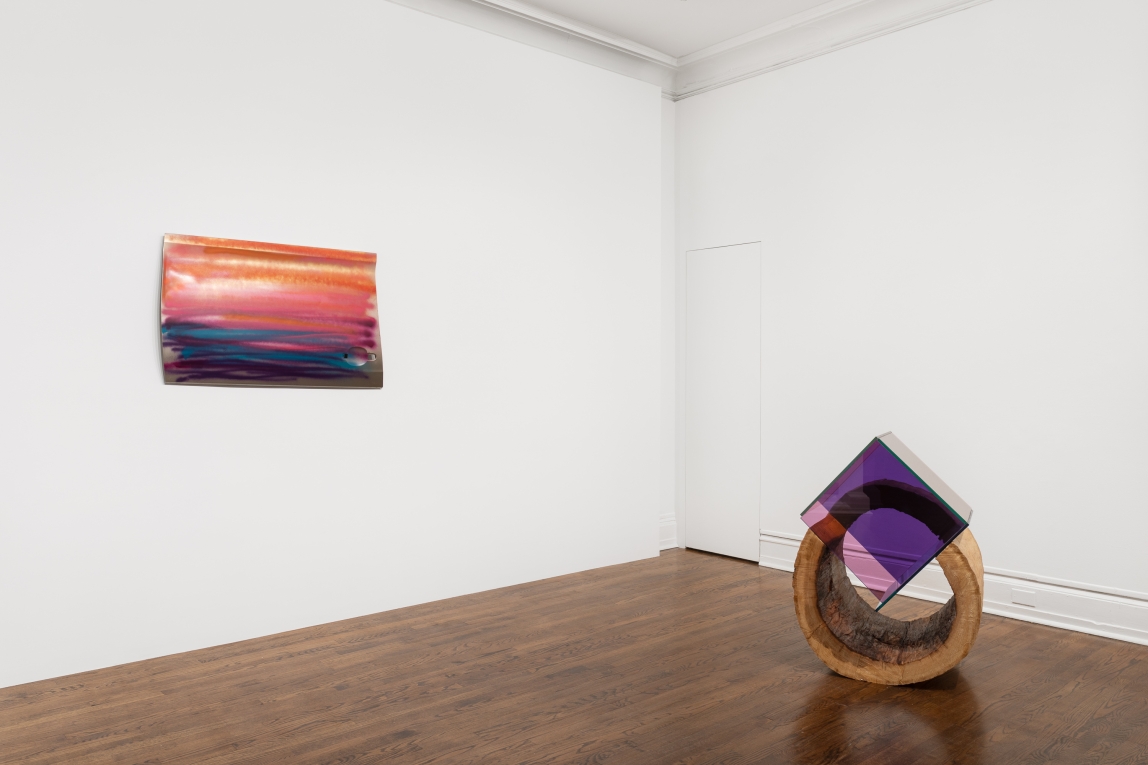 Installation view of a painted car door on the wall and a hollowed out log with glass cube on floor