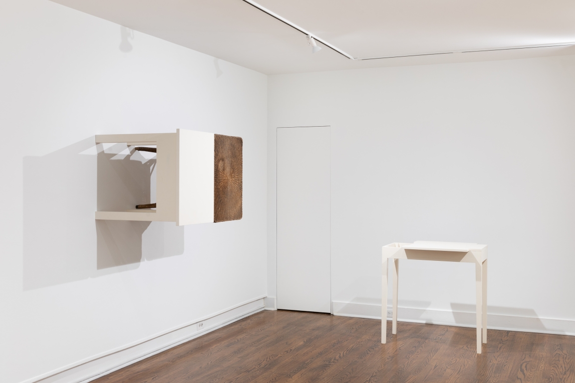 Installation view of white table to right and two tables hanging on the wall next to one another