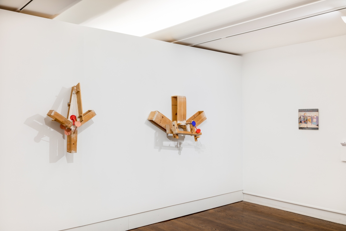 Installation view of two wooden scultptures on the wall to the left and a record cover hanging to the right