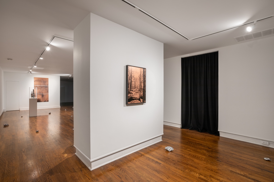 Installation view showing two different copper plate works on parallel walls, a ceramic sculpture on pedestal and rock artworks around the floor