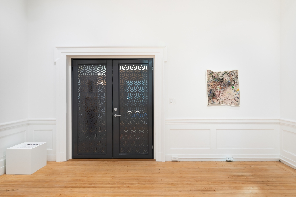 Installation view of framed painting on the wall next to closed metal doors
