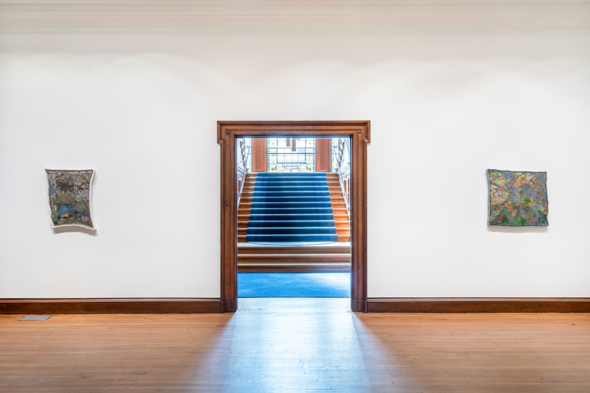 Installation view of two paintings on either side of large doorway