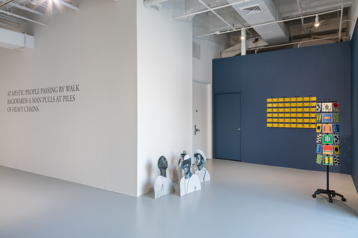 Installation view of text on wall, cards displayed and cardboard cutouts depicting Black soldiers