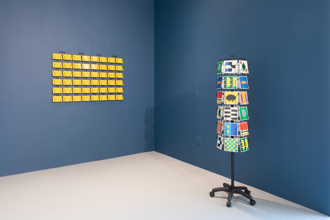 Installation view of cards displayed against a painted wall