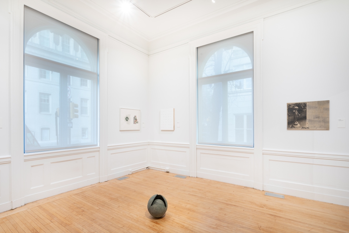 Installation image of corner of gallery with three works on the walls and a spherical sculpture on the foreground