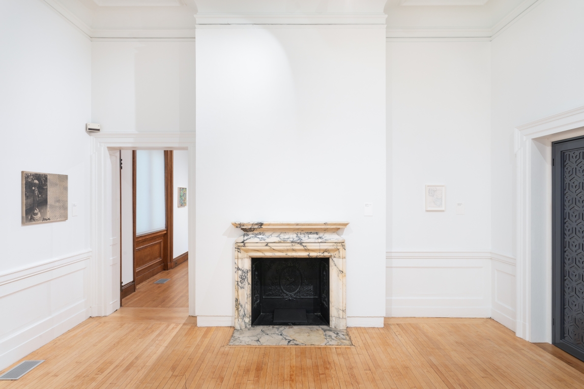 installation view of Gallery A with two works on two different walls and fireplace in middle