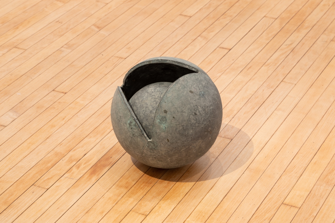 Installation view of metal spherical object showing a sphere within a sphere