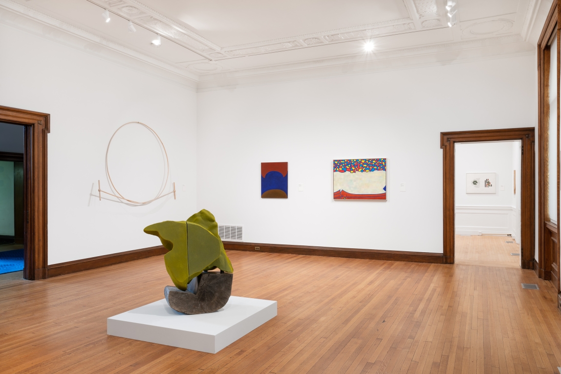 Installation view of Gallery B with green sculpture in foreground and three hanging works in background
