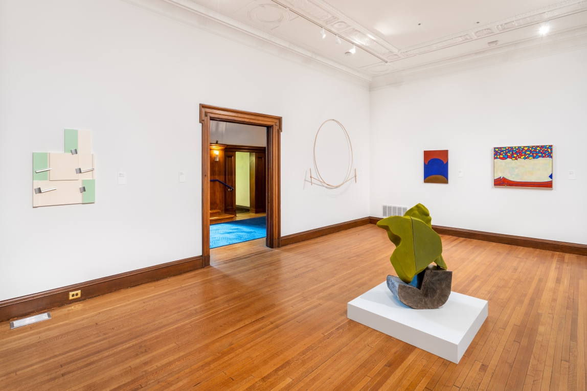 Installation view of Gallery B with four works hanging on adjoining walls and green sculpture in foreground