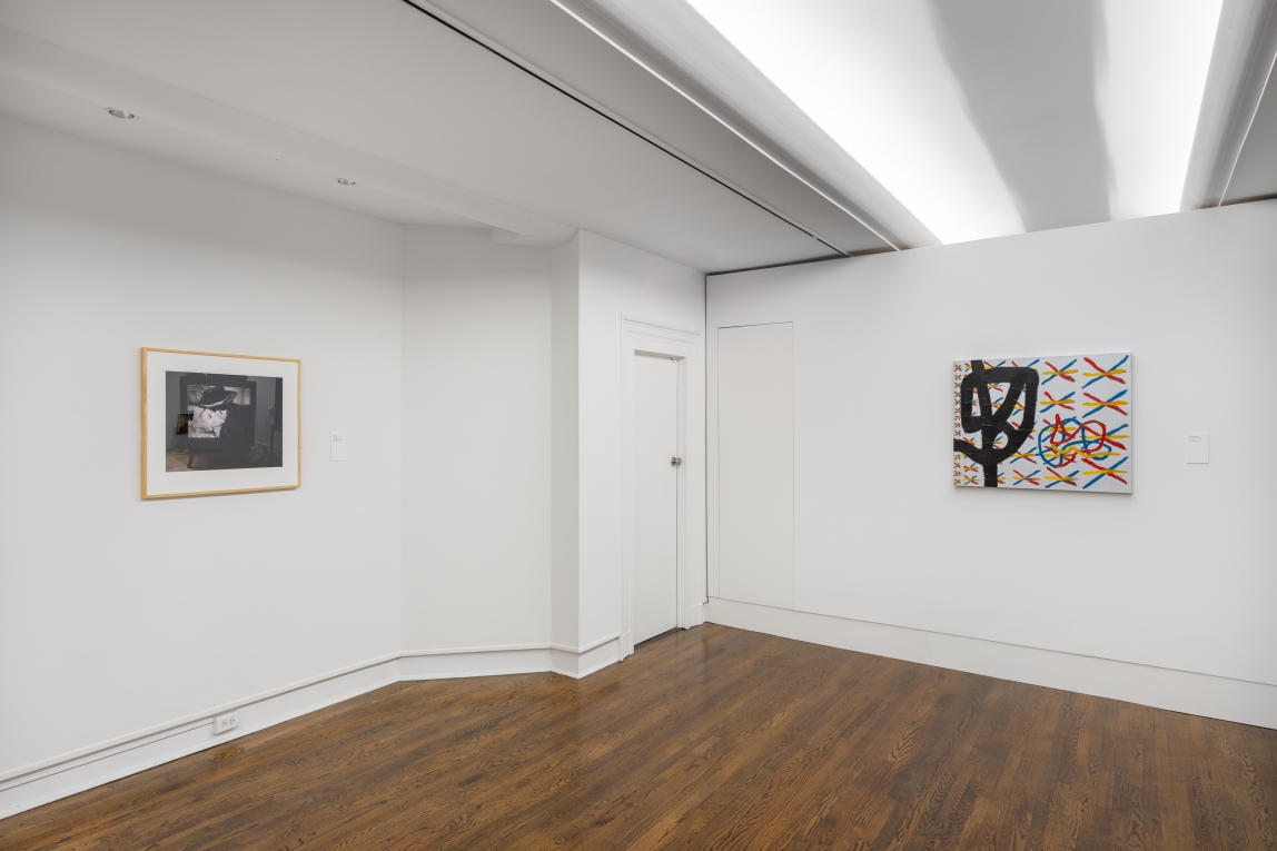 Installation view of a framed image to the left and a silver abstract painting to the right