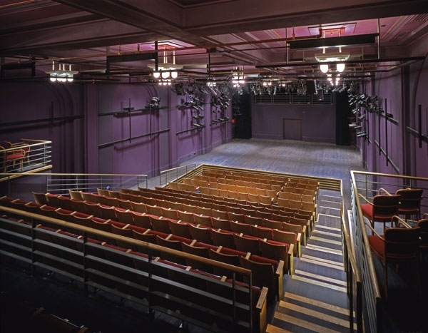interior shot of arts bank theater, with a view from the top of the raked seating area looking down at the stage. the walls and ceiling are painted purple and contain lighting installations. 