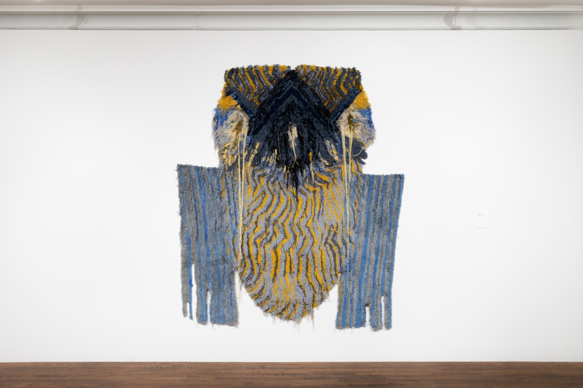 Installation view of large fiber woven artwork hung on wall