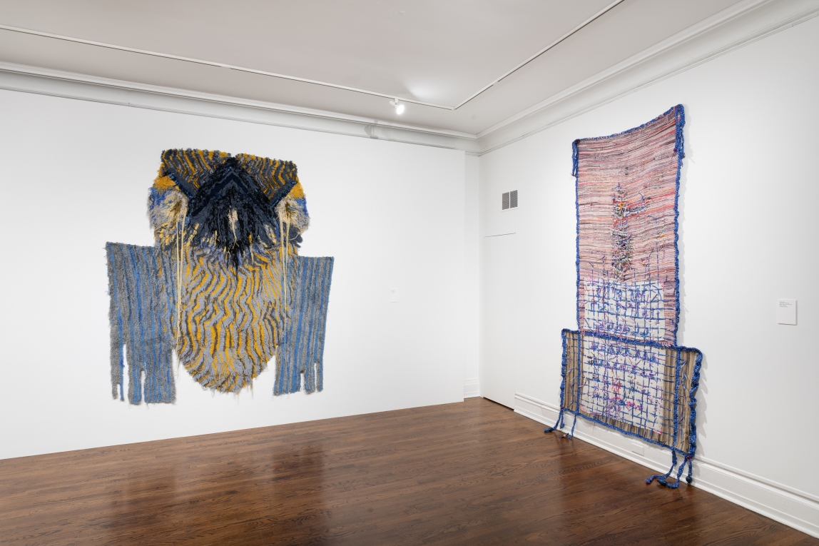 Installation view of two large fiber artworks hanging on adjoining walls