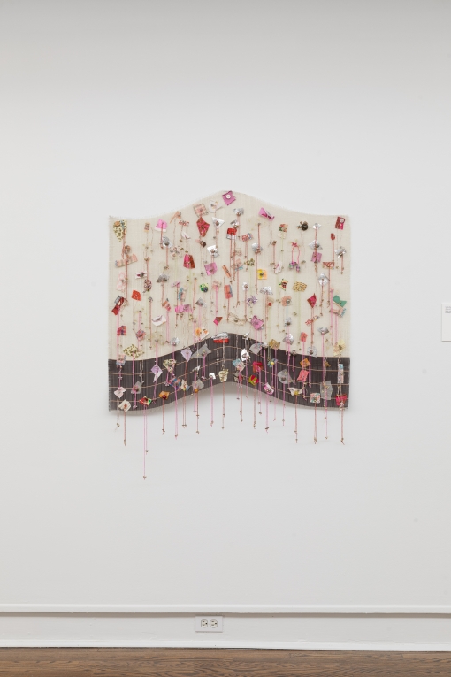 Installation view of fiber artwork made of delicate woven metal, strings and scraps of fabric