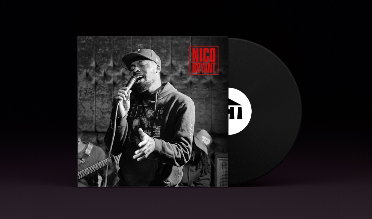 stylized vinyl album with a black record stamped with the UArts logo poking out. On the record sleeve is Nico Bryant in black and white singing into a microphone in an upholstered room wearing a baseball cap, black hoodie, with a tight beard. 
