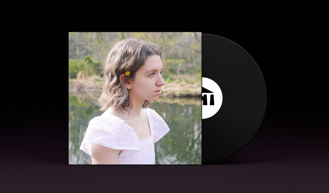 A stylized vinyl record album cover with a black record stamped with the UArts logo poking out. On the sleeve is student Mackenzie Markstein seen in profile in a white dress against a background of a green creek. 