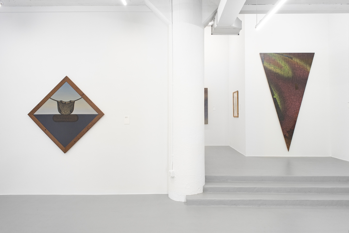 Installation image with diamond shaped basket painting in foreground and triangle painting in background