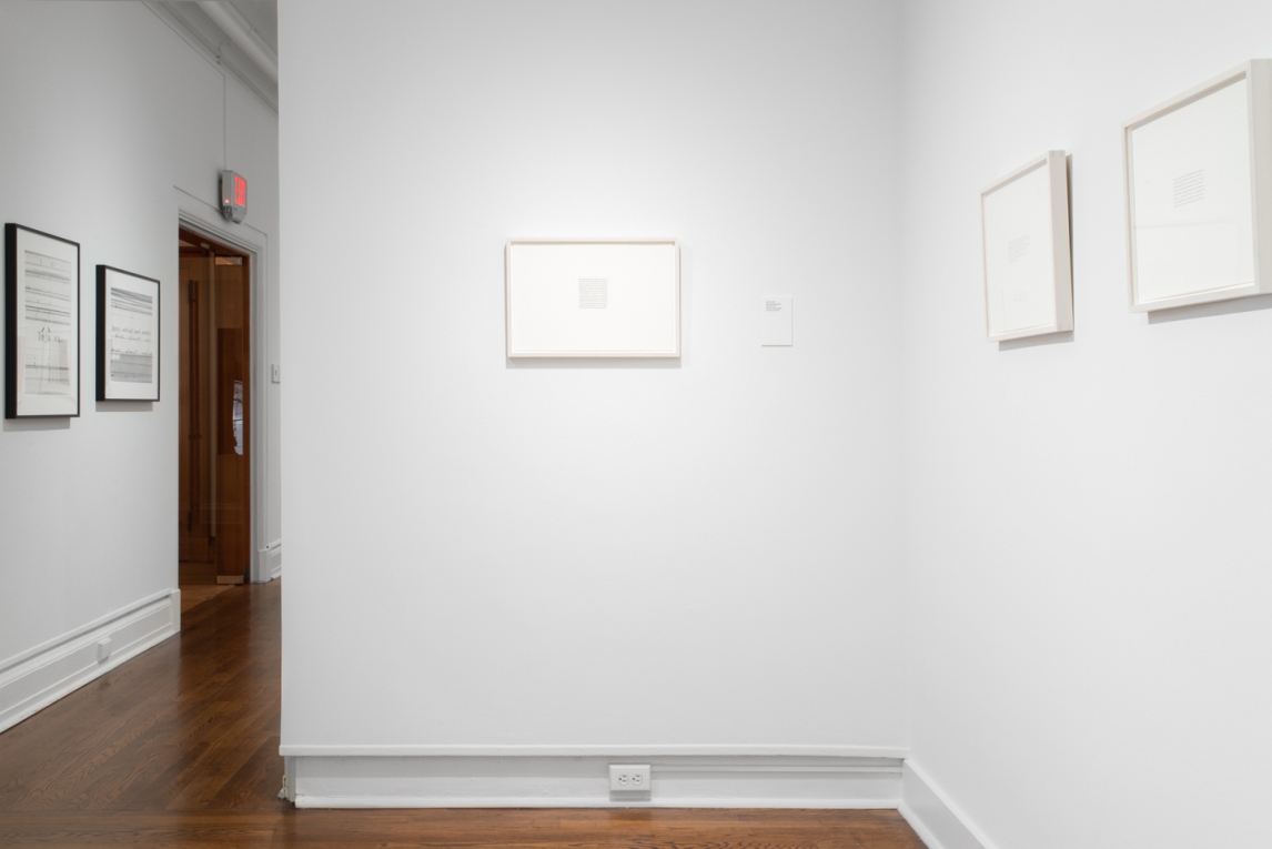Installation view of a work in pencil composed of text, with other work on adjoining walls