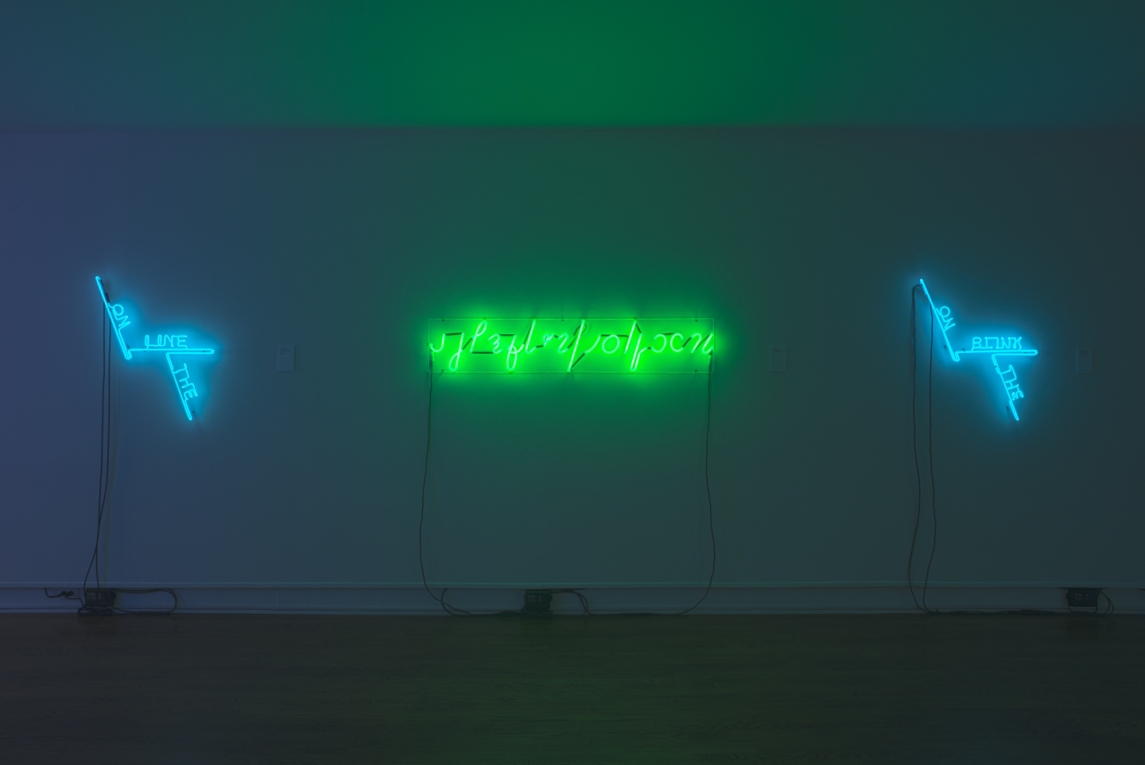 Installation view of three neon works composed of words hanging on a wall