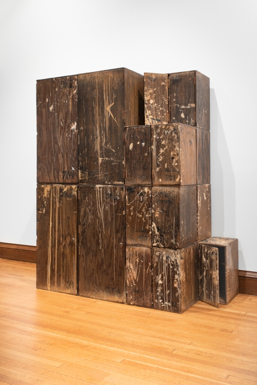 Installation view of tall stacked wooden cabinet boxes against a wall 
