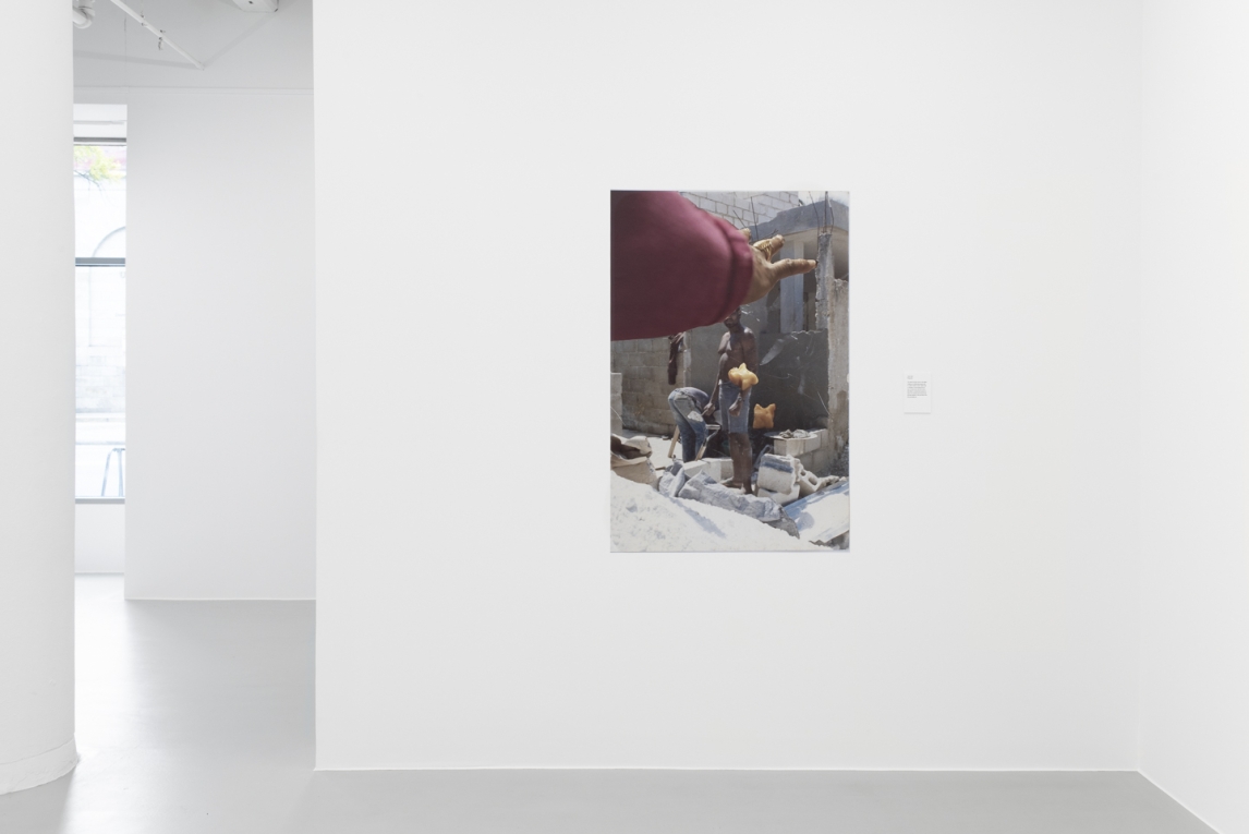 Installation view of vinyl mage of a Black person's hand releasing game pieces against an image oof a construction site 