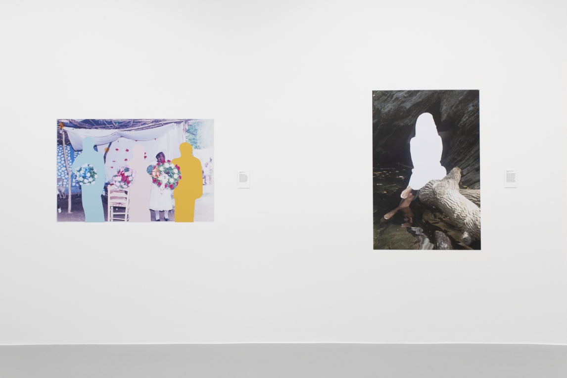 Installation view of two vinyl images dipictinig figures and people, displayed against a white wall