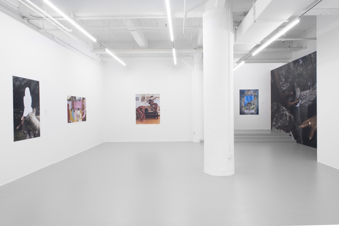 Installation view of gallery with vinyl images displayed and a large vinyl mural in side background