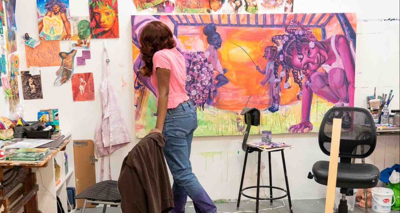 Student working in a studio on a large scale painting