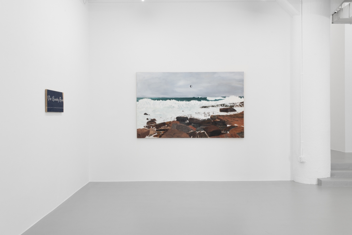 installation view of painting of coast on wall and another painting on adjoining wall