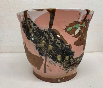 A wide vase painted abstractedly with pink and brown and green and white as well as bits of black lace