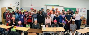 A large group of students wearing brightly colored hats in a cheerful classroom
