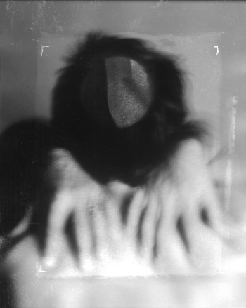 A black and white and blurry image of hands in the foreground with the subject's head bowed in the background