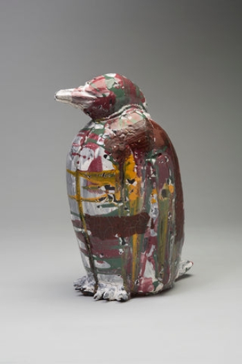 A ceramic sculpture of a penguin-like bird painted abstractedly in red, brown, green, yellow and white