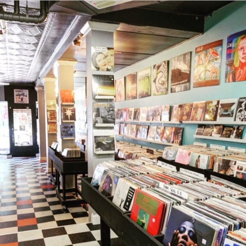 A photo of the inside of a record store, where isles of records are seen