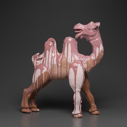 A mauve and pink and brown and tan ceramic sculpture of a camel looking behind it