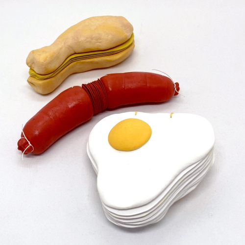 Three books that look like sculptures of an egg and a sausage and a sandwich