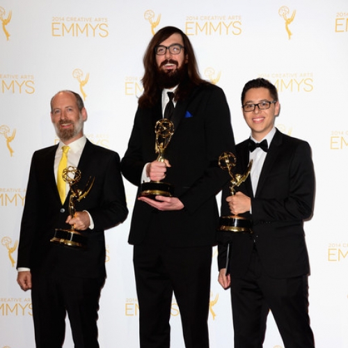 UArts alum Derek Dressler in center of two colleagues dressed in tuxedos on Emmy Awards red carpet, holding Emmy statuettes