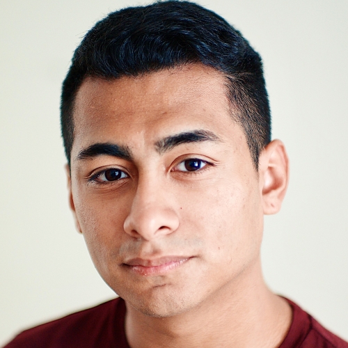 headshot of frank jimenez. frank has a serious but warm look on his face with dark eyebrows and tightly cropped dark hair. frank is wearing a burgundy crewneck t shirt against a blank cream background