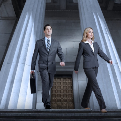 Two people in suits walking out of a building