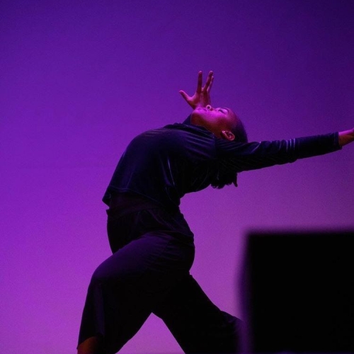 A photo of Hana Carlson dancing in front of a purple backdrop