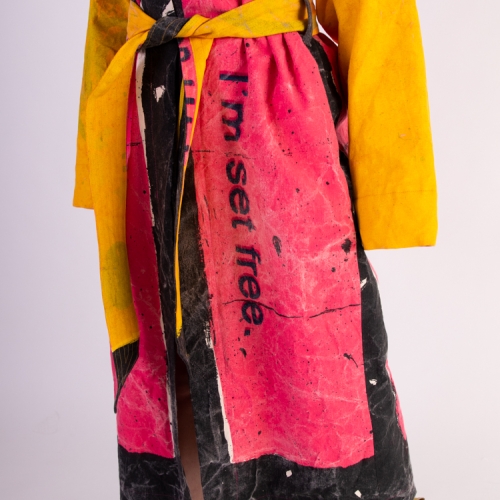 A model wearing a rose, yellow and black robe that says I'm set free on the front