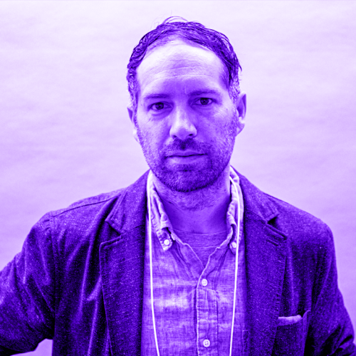headshot of ryan penn overlaid with a violet hue. ryan is wearing a light blazer of a linen loosely button collared shirt and is looking at the viewer with a scruffy face. 