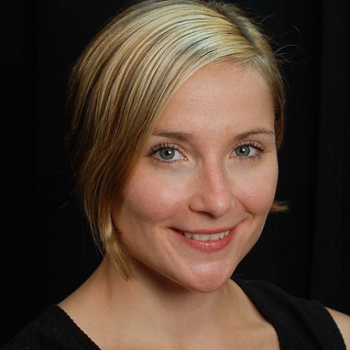 headshot of andrea weber with blonde hair against a black background