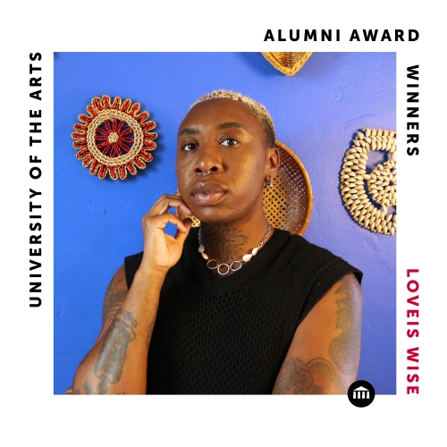 a square labelled image commemorate alumni award winner loveis wise. wise is pictured against a lilac background with woven artifacts on display. wise is wearing a black sleeveless shirt and a tight necklace, with bleached tightly. cropped hair and a collection of mid-sized tattoos. 