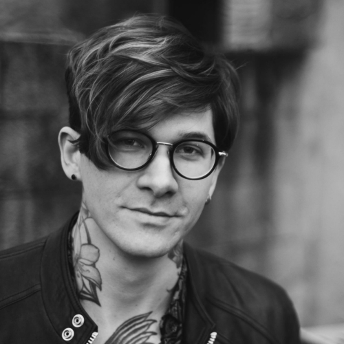 Head shot of Matt McAndrew, black and white, round glasses and neck tattoos