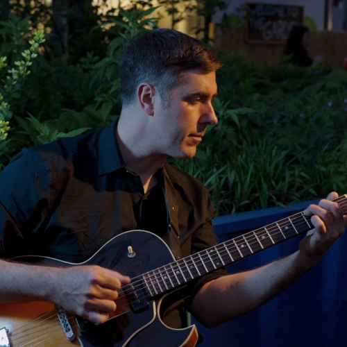 Matt Davis playing guitar outside in the evening