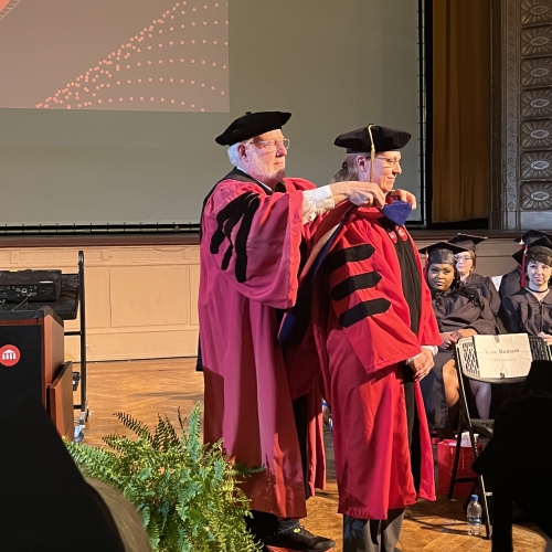 A UArts PhD student being hooded by her program director.